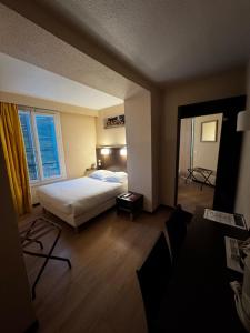 Una habitación de hotel con una cama y una ventana grande. en Hôtel Au Petit Caporal, en Maisons-Alfort