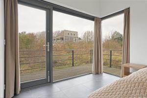a bedroom with a large sliding glass door with a view at Seaside Family Villa 6p - Direct bij het Strand - Villa 24 in Ouddorp