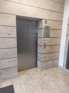a metal elevator door in a room with wooden walls at Apartament 24 Bolesławiec z garażem podziemnym in Bolesławiec +9 photos