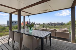 une salle à manger avec une table et des chaises sur une terrasse dans l'établissement Dune & Lakeview Villa 6p - Luxe, Lounge & Verwarmd Terras - Villa 30, à Ouddorp