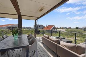 une terrasse avec une table et des canapés sur un balcon dans l'établissement Dune & Lakeview Villa 6p - Luxe, Lounge & Verwarmd Terras - Villa 30, à Ouddorp 38 autres photos
