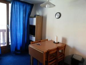 ヴァル・トランスにあるAltineige 4 Pers, Ski-inoutの青いカーテンと時計が置かれたダイニングテーブル