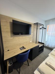 a room with a desk with a television on a wall at HI Grand City Hotel in Hannover