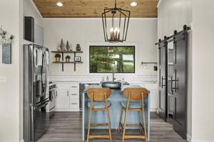 eine Küche mit einer Insel mit zwei Barhockern in der Unterkunft Luxury Hot-Tub WiFi - A Red River Barnhouse in Campton