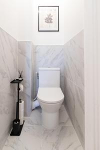 Baño blanco con aseo y una foto en la pared en Élégance & confort - aux portes de Paris, en Aulnay-sous-Bois 21 fotos más