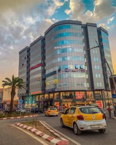 a yellow car parked in front of a large building at إقامة الرياض الأطلس in Beni Mellal