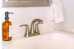- un lavabo avec une bouteille de savon à côté d'un robinet dans l'établissement Short North - Convention - Private Parking - Pets - 2BR, à Columbus 79 autres photos