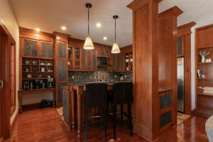 a kitchen with wooden cabinets and a bar with stools at Deluxe Ski in-out - HotTub - Fire - PingPong - View in Mont-Tremblant