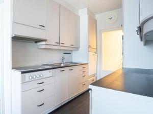 a white kitchen with white cabinets and a sink at Aurora Family Suite in Rovaniemi