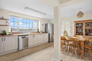 a kitchen with white cabinets and a table and a dining room at Rose Cottage in Port Isaac