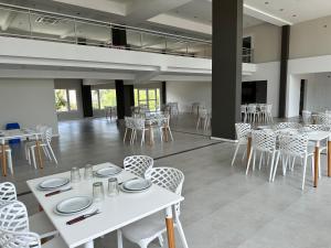 a dining room with white tables and chairs at Suite del Sol 106 in Pinamar