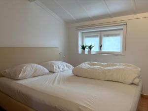 een slaapkamer met een bed met twee kussens en een raam bij Vakantiehuisje Wenduine in De Haan