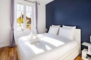 Un dormitorio con una gran cama blanca con una pared azul. en Élégance & confort - aux portes de Paris, en Aulnay-sous-Bois