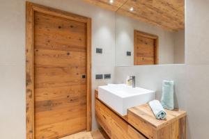 ein Badezimmer mit einem weißen Waschbecken und einer Holztür in der Unterkunft BRENTA ALTA ALPINE LODGE MhD in Madonna di Campiglio + 42 Fotos