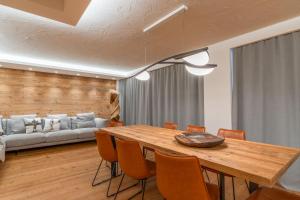 ein Esszimmer mit einem Holztisch und einem Sofa in der Unterkunft BRENTA ALTA ALPINE LODGE MhD in Madonna di Campiglio