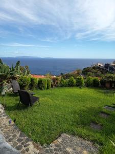 two chairs sitting in the grass near the ocean at The Goat's Place III in Gaula