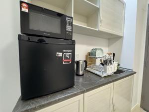 Un microondas encima de un refrigerador en una cocina. en Bay Suites l Seaview l 8 Pax l SICC l 沙巴全海景民宿, en Kota Kinabalu