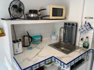 eine Küchentheke mit Spüle und Mikrowelle in der Unterkunft Cute and characterful townhouse in Oliva