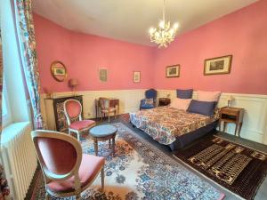a bedroom with pink walls and a bed and chairs at Le manoir d'Estiveaux in Le Châtelet