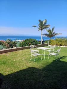 a table and chairs sitting on a lawn with the ocean at Eagle's Nest in Mossel Bay +2 photos