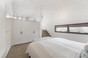 a white bedroom with a bed and a staircase at Grevelingenmeer Panorama Villa 4p - Luxe & Natuur - Villa 14 in Ouddorp
