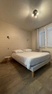 een slaapkamer met een groot bed met witte lakens en een raam bij LES VOYAGEURS - Vairé in Vairé