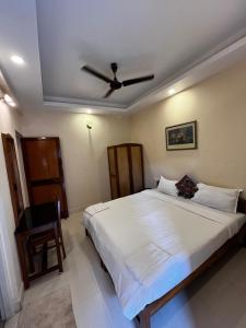 une chambre avec un grand lit avec un ventilateur de plafond dans l'établissement Tha Villa Calangute, à Calangute 3 autres photos