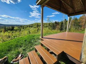 a wooden porch with benches and a view of the woods at Off-Grid Cabin Nestled Among Nature with Lovely Landscape Views in Maine in Lavertue