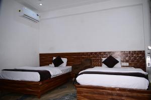 une chambre avec deux lits avec des draps blancs dans l'établissement Namami Atithi Grah, à Barsāna 11 autres photos