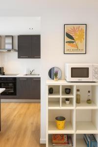 eine weiße Küche mit einer Mikrowelle und einer Theke in der Unterkunft Appartement avec terrasse entre vignes, balades, Alsace in Guebwiller