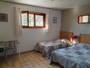 a bedroom with two beds and a desk and a window at Le Gite de Pigneux in Truison