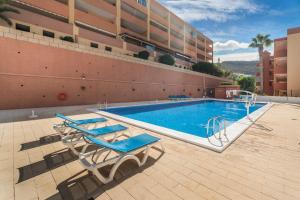 een zwembad met twee ligstoelen naast een gebouw bij Ocean View Costa Adeje in Adeje