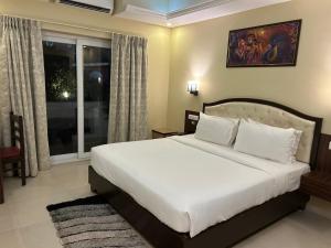a bedroom with a large white bed and a window at Casa goa in Calangute