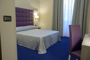 a bedroom with a large bed with a purple headboard at Hotel Torino Porta Susa in Turin