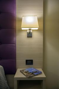 a table with a lamp and a magazine on it at Hotel Torino Porta Susa in Turin