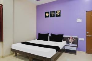 a bedroom with a large bed with a purple wall at Hotel O Atithi Lodge in Wagholi