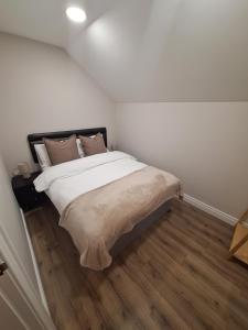 a bedroom with a bed with white sheets and wooden floors at Macaldrack's Loft in Dunloy
