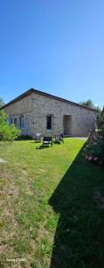 a brick building with two benches in a grass field at Chez Jollyjune, à moins d'une heure du Mont Saint Michel in Champeaux