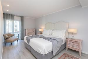 a white bedroom with a large bed and a chair at BeGuest Jardim Quinta da Alagoa Luxury Stay in Carcavelos