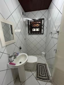 a white bathroom with a toilet and a sink at Sítio Vô Leno in Biguaçu