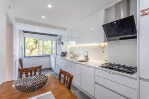 a kitchen with white cabinets and a table and chairs at BeGuest Jardim Quinta da Alagoa Luxury Stay in Carcavelos