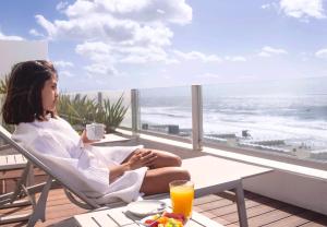 a woman sitting in a chair on a balcony looking out at the ocean at Terrazas Al Mar in Pinamar