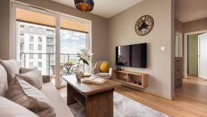 ein Wohnzimmer mit Sofa und Fernseher in der Unterkunft Flatbook - Seaside Apartments Nowa Letnica with a Rooftop Viewing Terrace & Gym II in Danzig