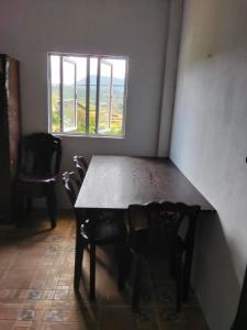 ein Tisch und Stühle in einem Zimmer mit Fenster in der Unterkunft Nuwara eliya rashini mountain view cottage in Nuwara Eliya