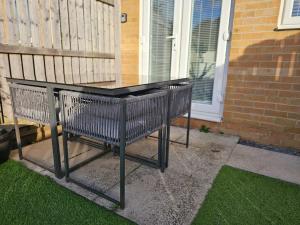 une table noire avec deux chaises devant une maison dans l'établissement Spacious 3-Storey Home from Home in Hetton le Hole, à Hetton le Hole