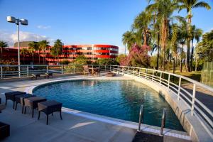 a swimming pool with a bridge and chairs and a building at Golden Tulip Brasília Alvorada in Brasilia