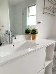 Un baño blanco con lavabo y espejo. en Vivi's Home, en Vancouver