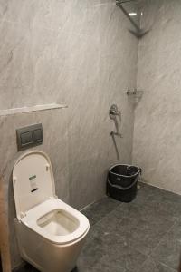 a bathroom with a toilet and a black bucket at Madhura Luxury Rooms in Hyderabad