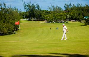 a man playing golf on a green with a red flag at Sun Wind Villa in Saint Johnʼs