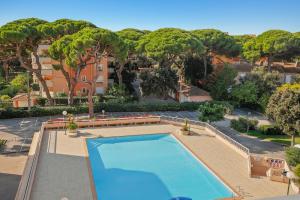 ein großer Pool mit Bänken und ein Gebäude in der Unterkunft Piscine & Soleil à Hyères - T3 spacieux avec Clim & Extérieurs in Hyères